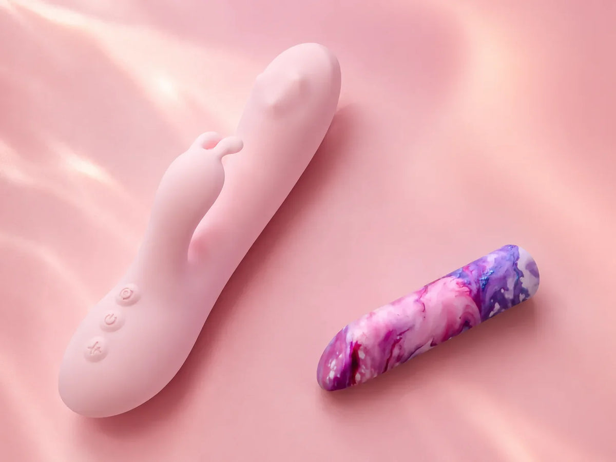 Pink rabbit vibrator and marbled bullet vibrator displayed side by side on a soft pink background