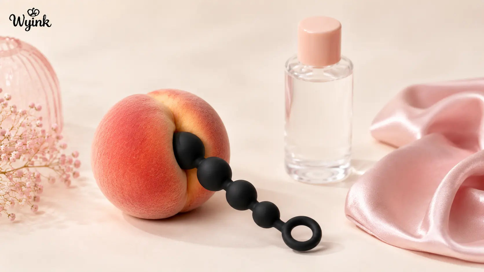 Matte black silicone anal beads partially inserted into a peach to demonstrate gradual insertion for beginners