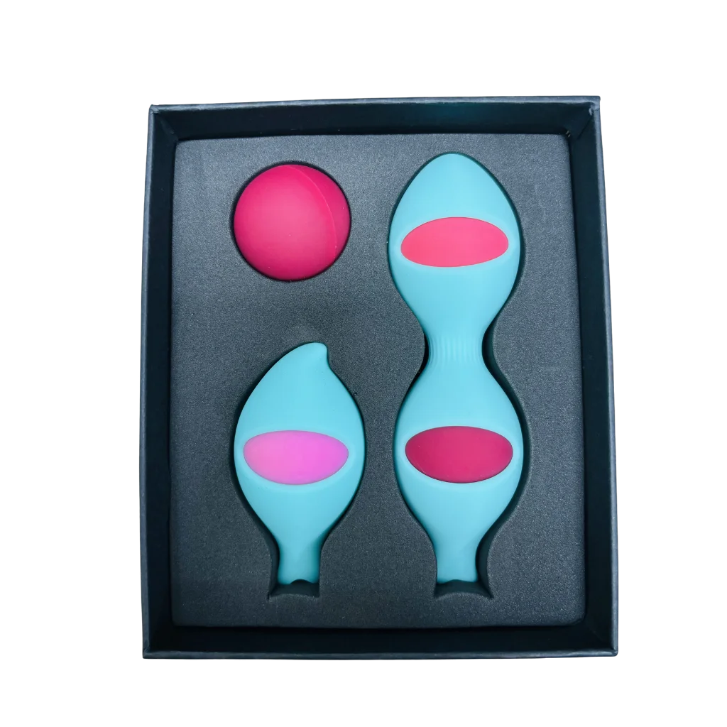 A boxed intimate wellness set containing two light blue silicone plugs with pink centers and a separate pink ball, presented in a black gift box on a white background.
