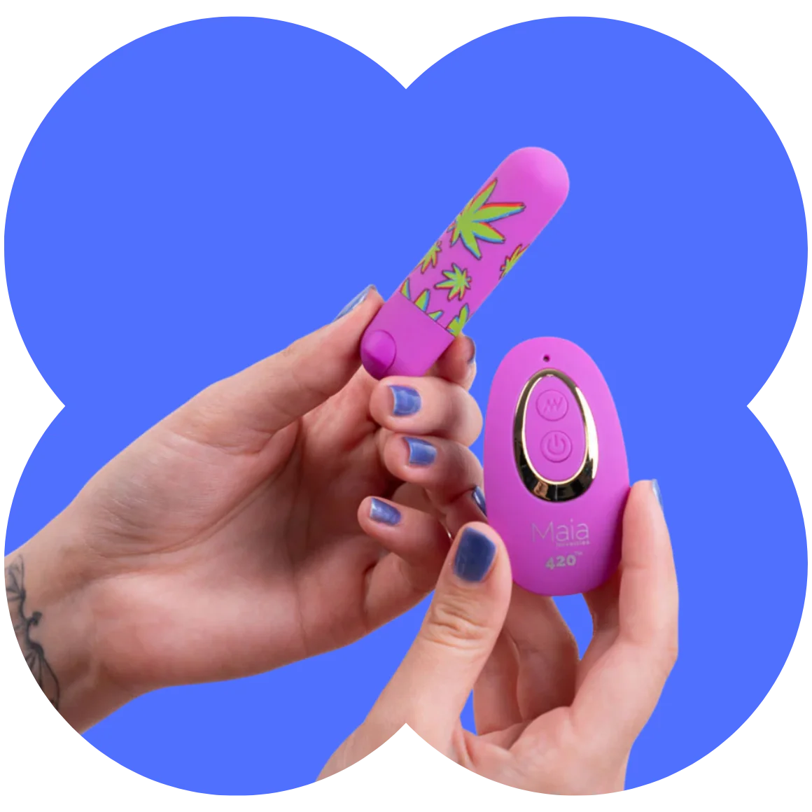 A person's hands holding a pink personal massager and its matching remote control against a blue graphic background. The massager has green leaf patterns, and the remote is pink with a gold accent ring.