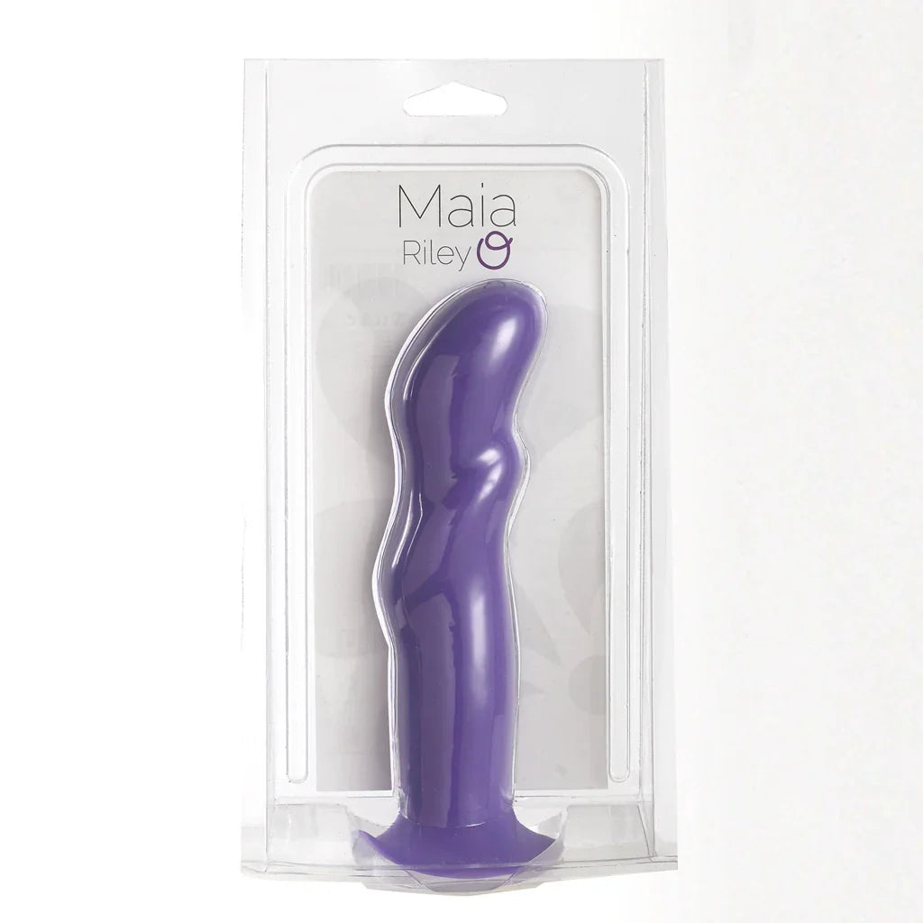 Purple curved silicone personal massager in clear retail packaging with a printed backing card labeled 'Maia Riley'.