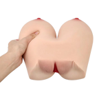 A silicone adult novelty titwoman  with realistic skin-toned texture, red nipple details, and a red opening at the center, shown with a hand pressing on one side against a white background.
